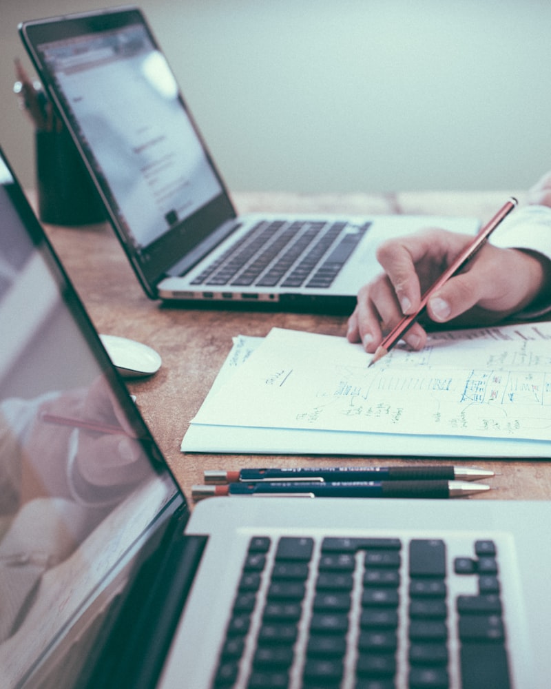 Two people sketching product wireframes beside laptops